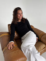 Modelfoto af pige som bærer en langærmet Henna bluse i sort, samt hvide Nanna jeans. Alt fra By Sofie Sønderby