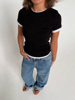 Modelfoto af pige som bærer en Henna t-shirt i sort, samt blå Nanna jeans. Alt fra By Sofie Sønderby