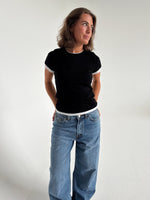 Modelfoto af pige som bærer en Henna t-shirt i sort, samt blå Nanna jeans. Alt fra By Sofie Sønderby