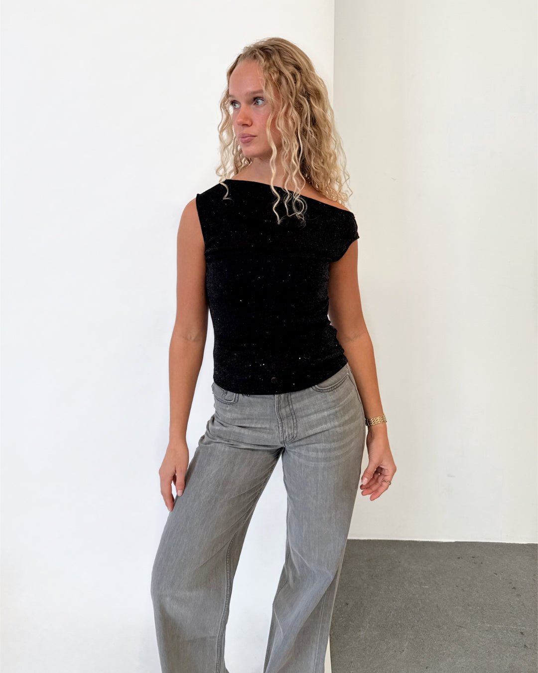 Modelfoto af pige i sort HOLLY top, samt grå NANNA jeans. Alt er fra BySofieSønderby.