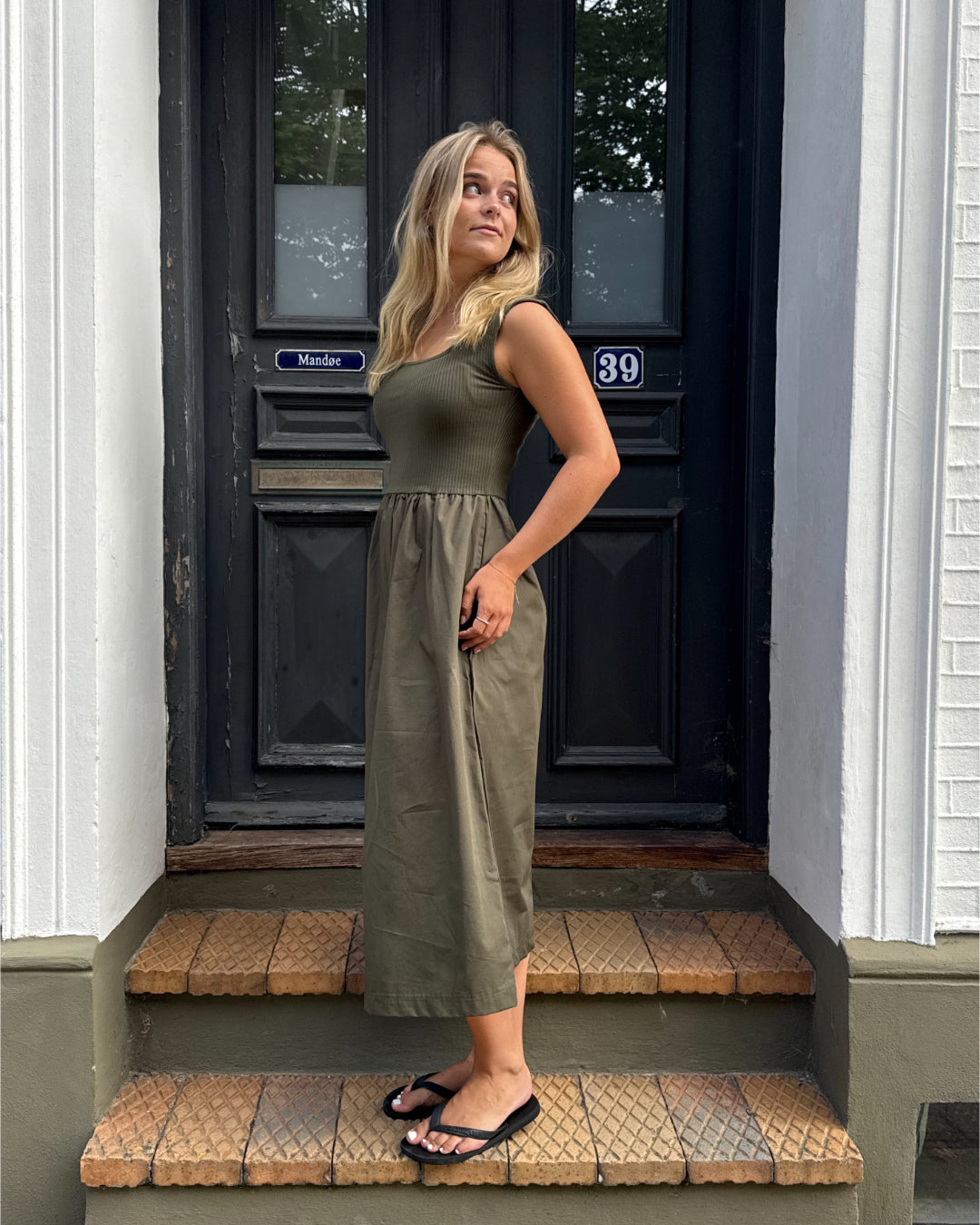 Modelfoto af pige, som bærer SIMONE kjole, kaki og sandal, sort - alt fra BySofieSønderby.