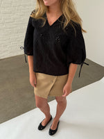 Modelfoto af pige iklædt JOELLA bluse, sort og NOAH nederdel, sand - begge fra BySofieSønderby