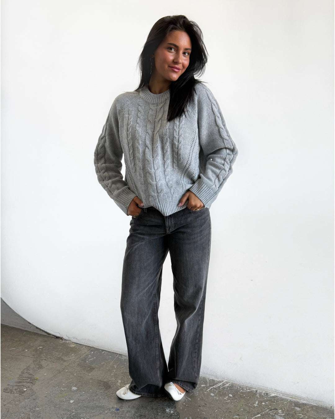 Modelfoto af pige i grå Josie striktrøje, og grå Nanna jeans. Alt er fra BySofieSønderby 