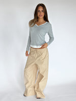 Modelbillede af KAIA langærmet v-hals, grå og DANIA wide leg bukser, beige. Begge fra BySofieSønderby