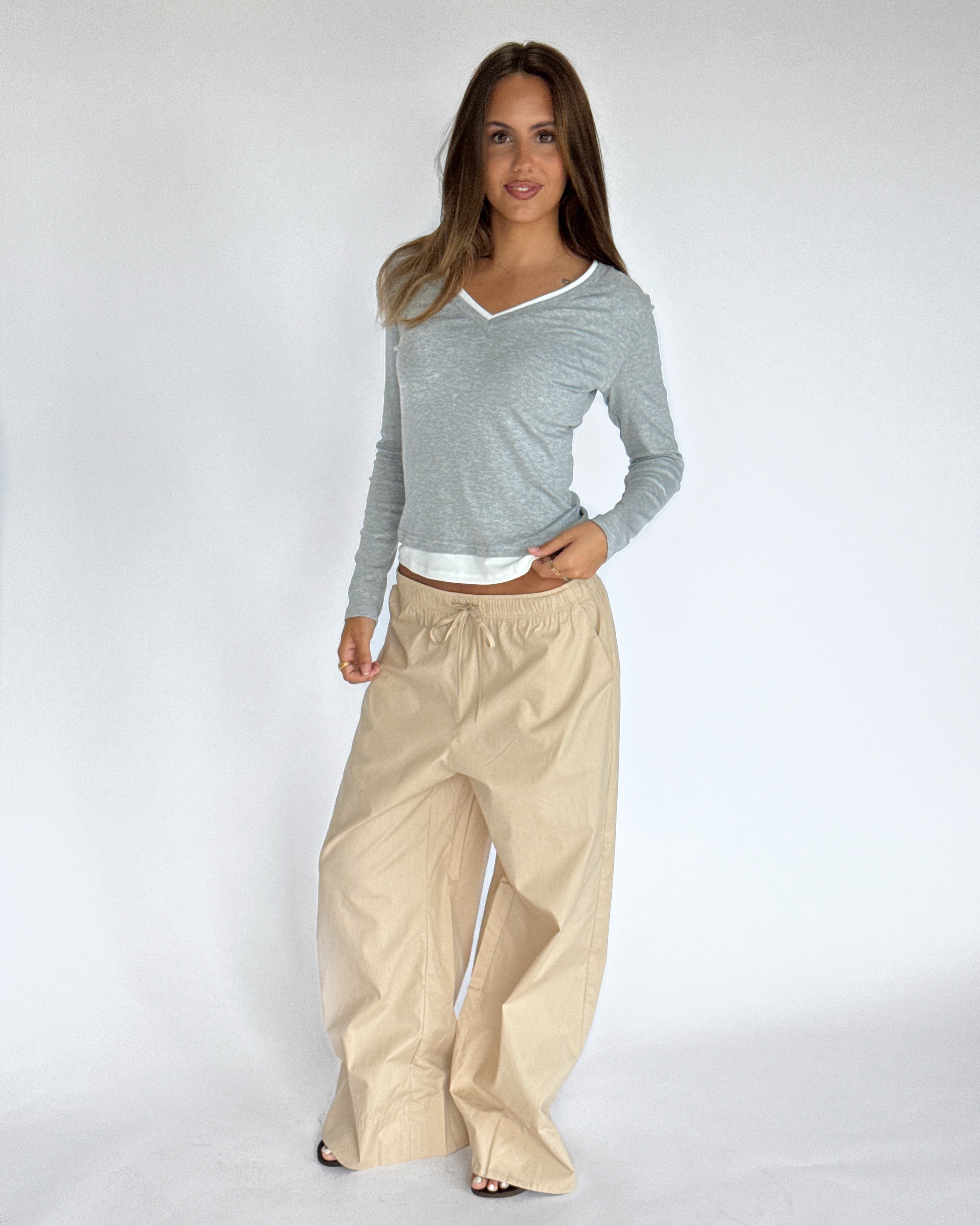 Modelbillede af KAIA langærmet v-hals, grå og DANIA wide leg bukser, beige. Begge fra BySofieSønderby