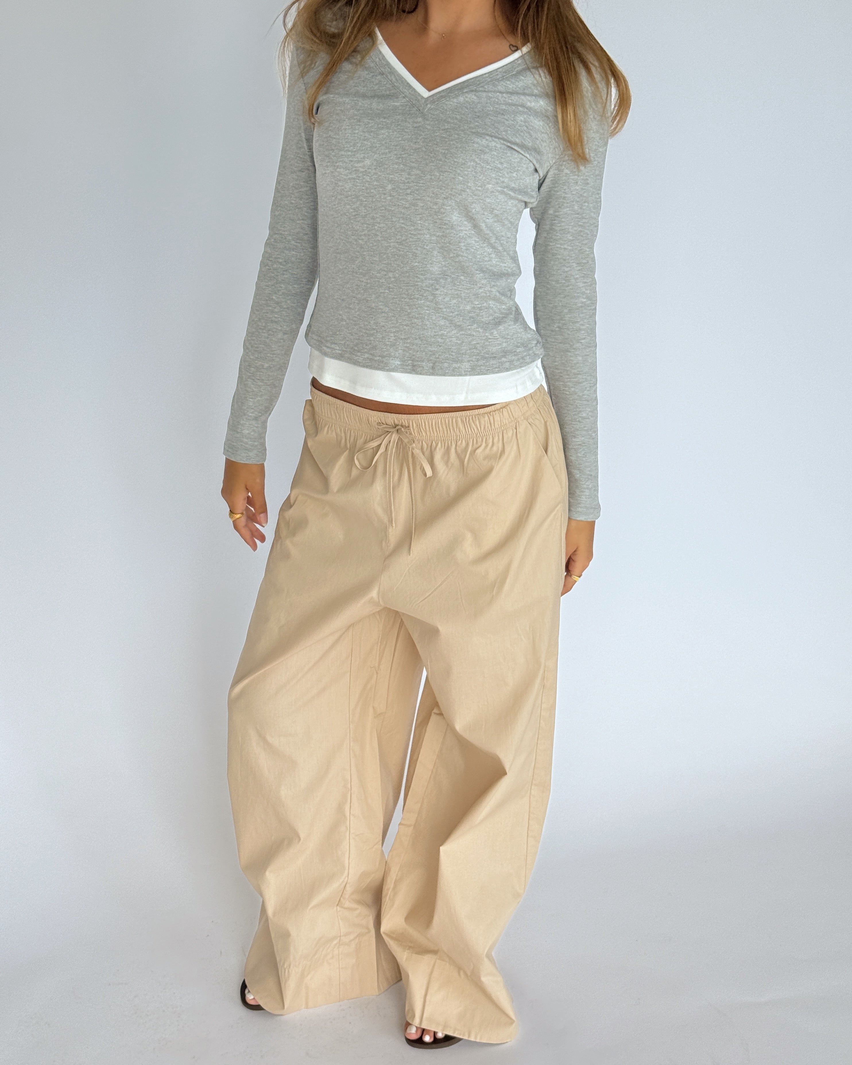 Modelbillede af KAIA langærmet v-hals, grå og DANIA wide leg bukser, beige. Begge fra BySofieSønderby