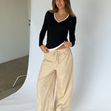 Modelbillede af KAIA langærmet v-hals, sort og DANIA wide leg bukser, beige. Begge fra BySofieSønderby