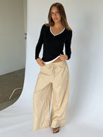 Modelbillede af KAIA langærmet v-hals, sort og DANIA wide leg bukser, beige. Begge fra BySofieSønderby