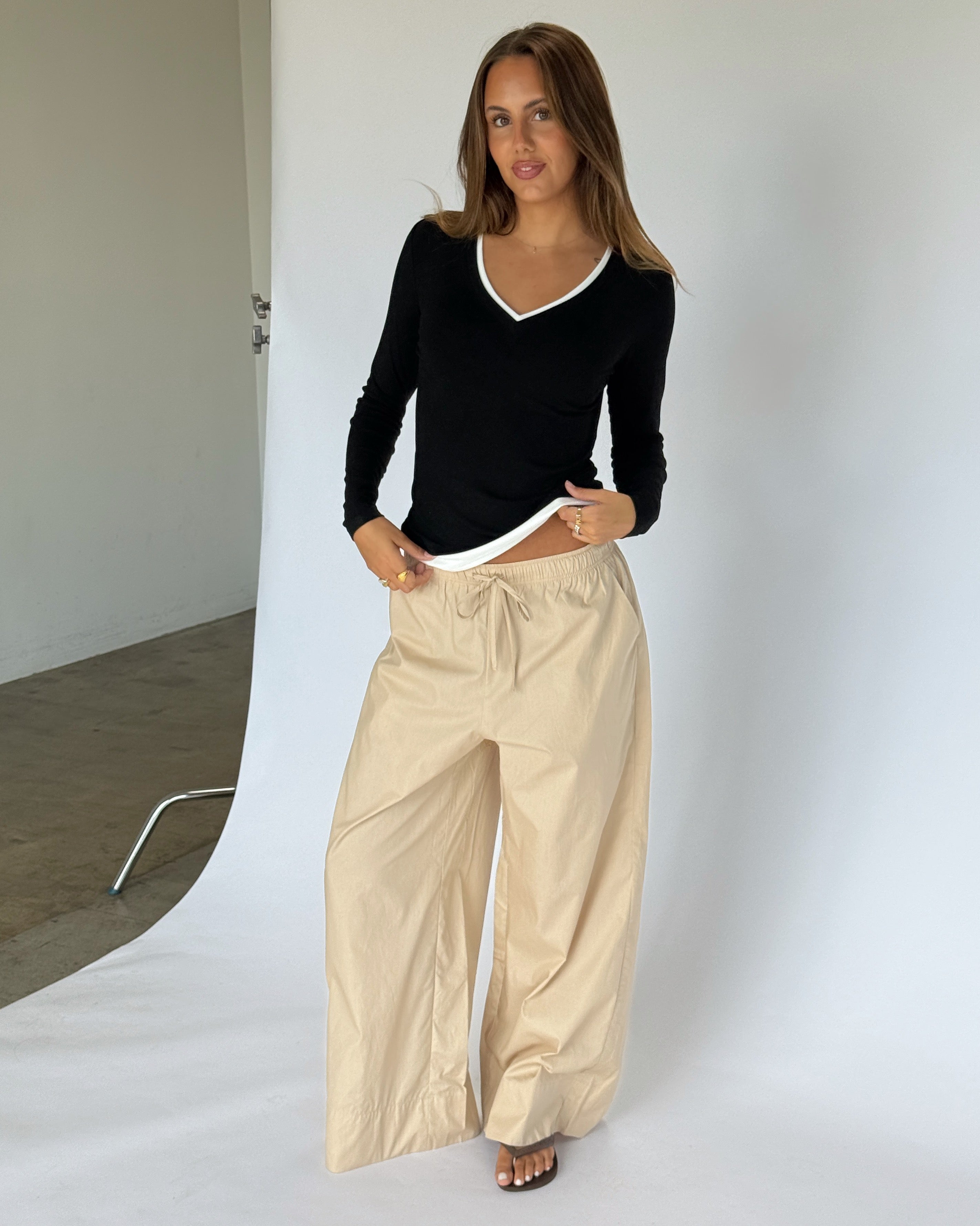 Modelbillede af KAIA langærmet v-hals, sort og DANIA wide leg bukser, beige. Begge fra BySofieSønderby