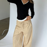 Modelbillede af KAIA langærmet v-hals, sort og DANIA wide leg bukser, beige. Begge fra BySofieSønderby