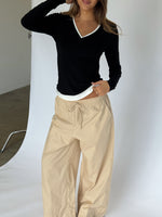 Modelbillede af KAIA langærmet v-hals, sort og DANIA wide leg bukser, beige. Begge fra BySofieSønderby