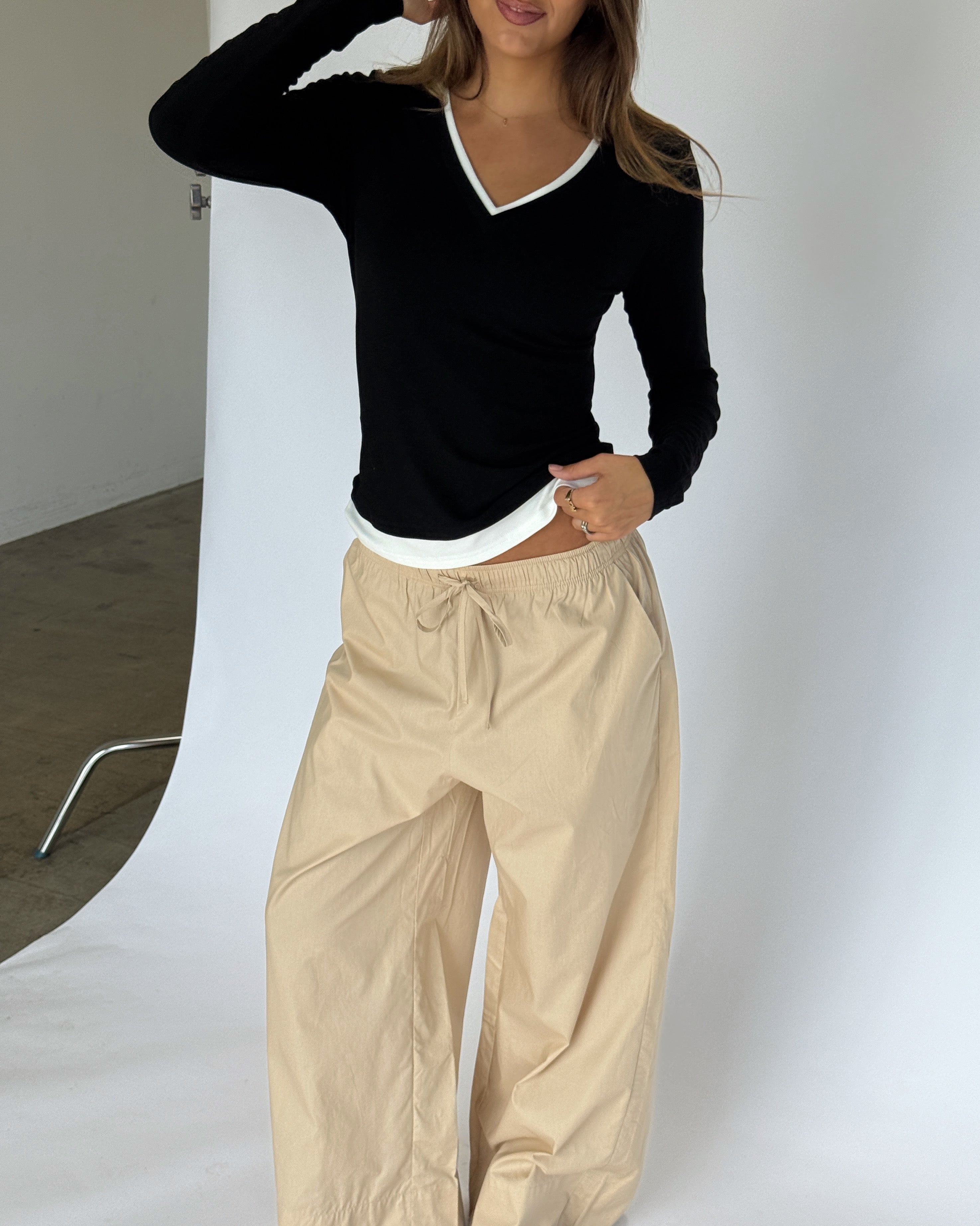 Modelbillede af KAIA langærmet v-hals, sort og DANIA wide leg bukser, beige. Begge fra BySofieSønderby