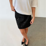 Modelfoto af pige i sort KENDALL nederdel med pailetter, samt hvid basic t-shirt og spidse ballerinaer. Alt er fra BySofieSønderby.