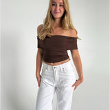 Modelfoto af pige som bærer en Leia top i brun, samt et par hvide Nanna jeans. Alt fra By Sofie Sønderby
