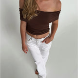 Modelfoto af pige som bærer en Leia top i brun, samt et par hvide Nanna jeans. Alt fra By Sofie Sønderby