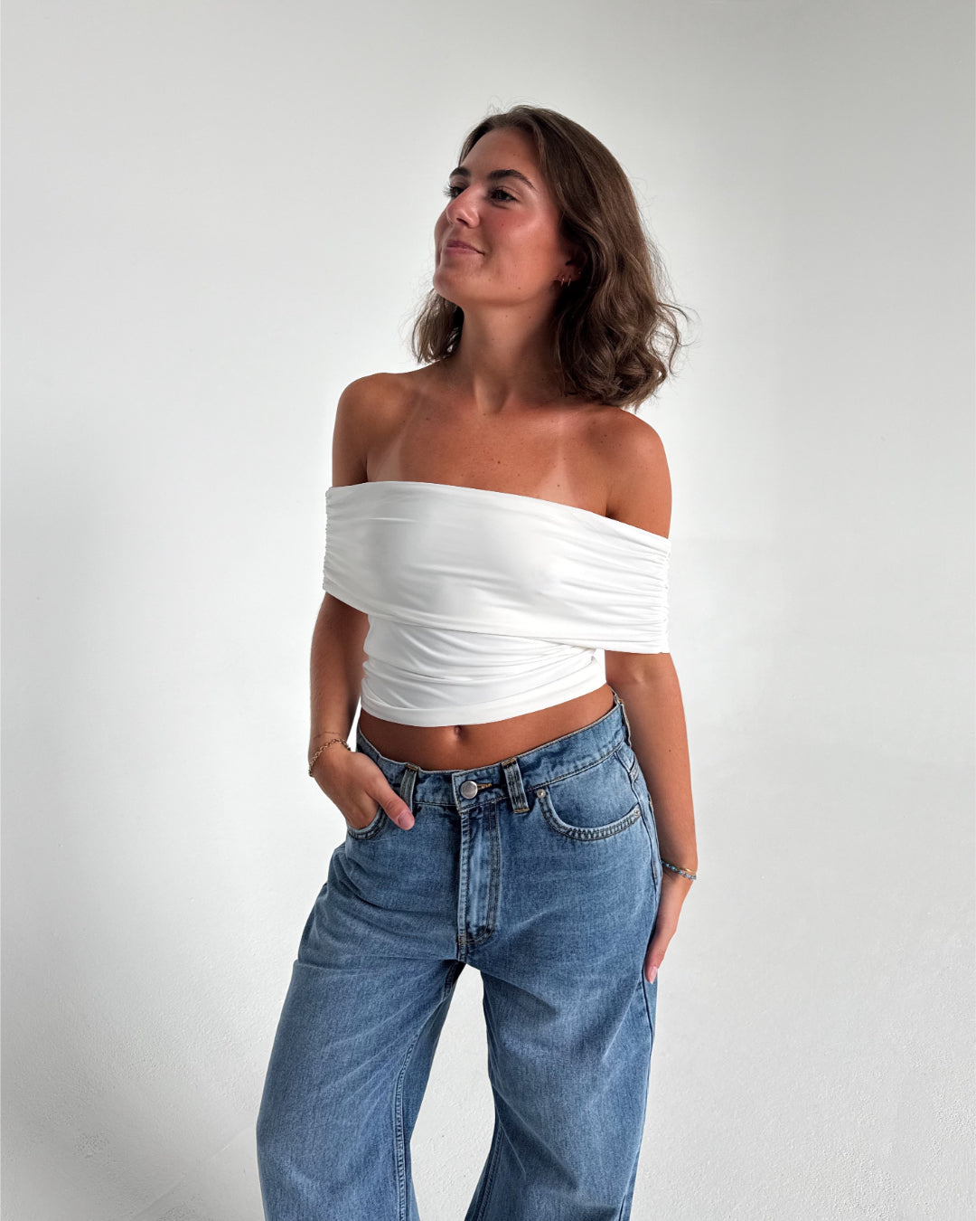 Modelfoto af pige som bærer en Leia top i hvid, samt et par hvide Nanna jeans. Alt fra By Sofie Sønderby