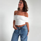 Modelfoto af pige som bærer en Leia top i hvid, samt et par hvide Nanna jeans. Alt fra By Sofie Sønderby