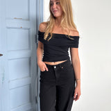 Modelfoto af pige som bærer en Leia top i sort, samt et par hvide Nanna jeans. Alt fra By Sofie Sønderby