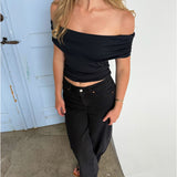 Modelfoto af pige som bærer en Leia top i sort, samt et par hvide Nanna jeans. Alt fra By Sofie Sønderby
