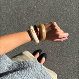 Modelfoto af Leona armbånd sæt bestående af 3 armbånd i brunlige nuancer. Baggrund er grå. Fra BySofieSønderby