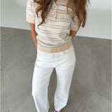 Modelfoto af pige som bærer en LILLIANA beigestribet polo t-shirt og hvide jeans. Alt er fra BySofieSønderby