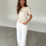Modelfoto af pige som bærer en LILLIANA beigestribet polo t-shirt og hvide jeans. Alt er fra BySofieSønderby