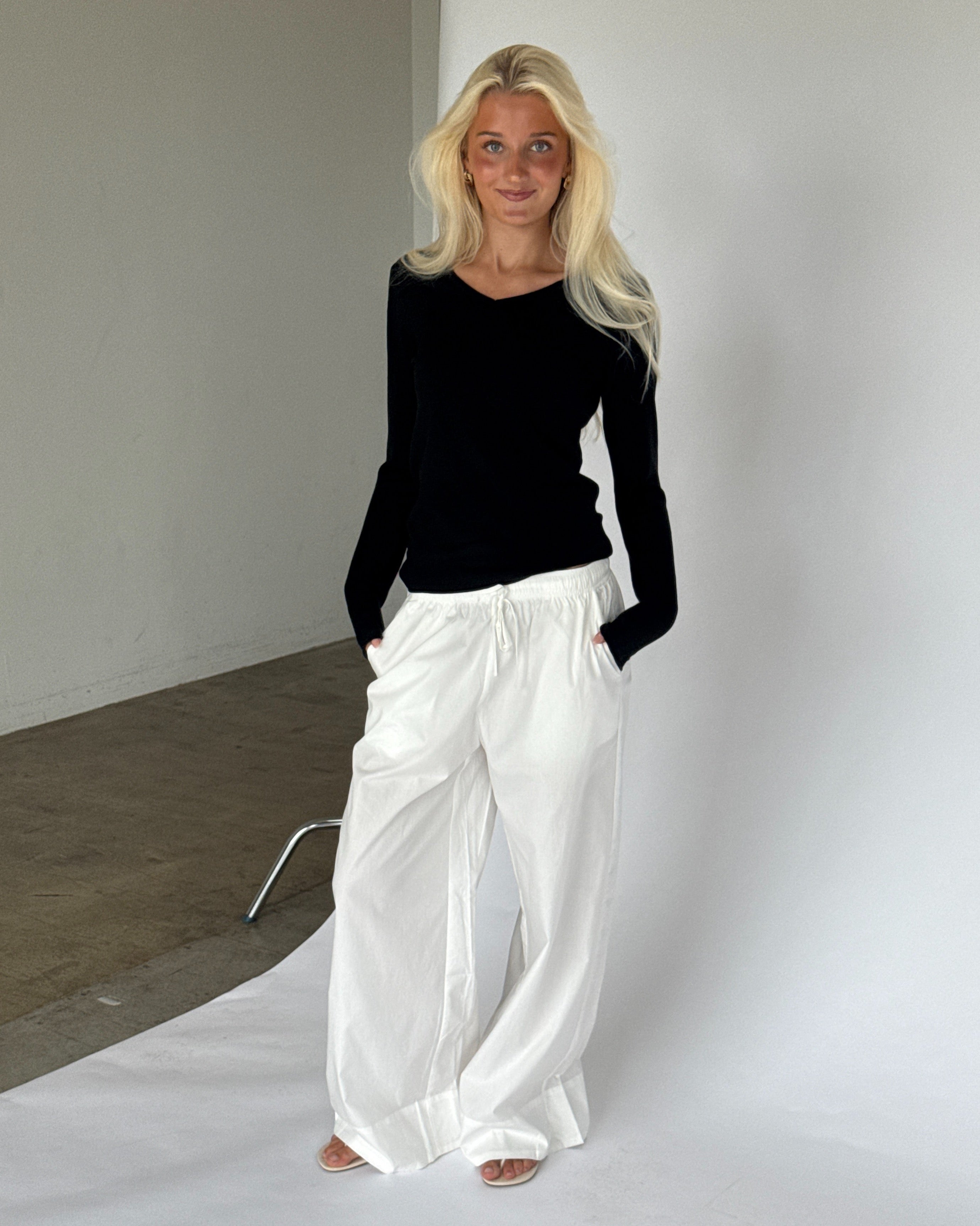 Modelbillede af LILLIE langærmet v-hals, sort og DANIA wide leg bukser, hvid. Begge fra BySofieSønderby
