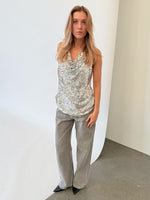 Modelfoto af pige i sølvfarvet LINA top med pailetter, samt grå NANNA jeans. Alt er fra BySofieSønderby.
