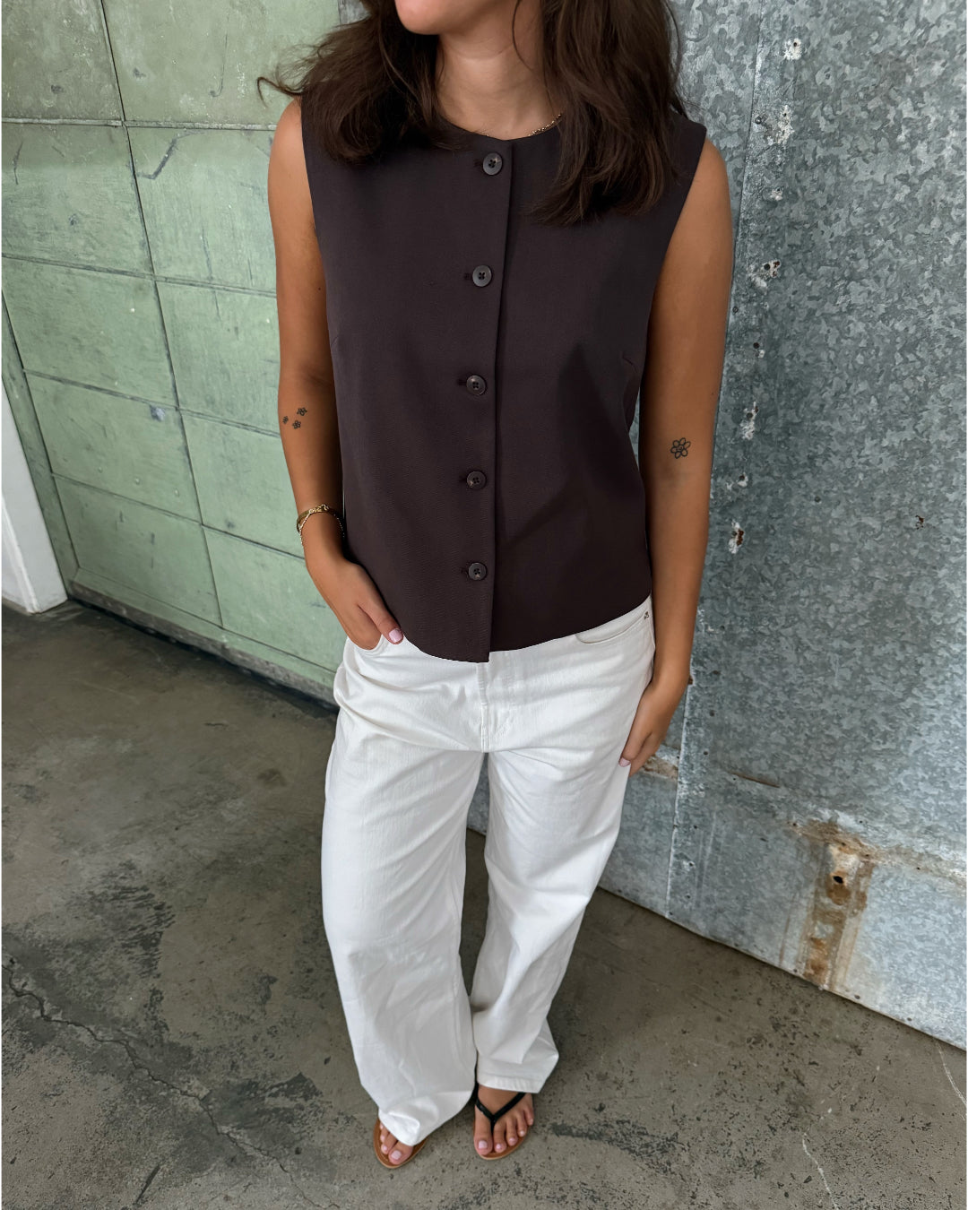 Modelfoto af pige der bærer Lisa vest i brun, samt hvide nanna jeans. Alt fra BySofieSønderby