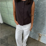 Modelfoto af pige der bærer Lisa vest i brun, samt hvide nanna jeans. Alt fra BySofieSønderby