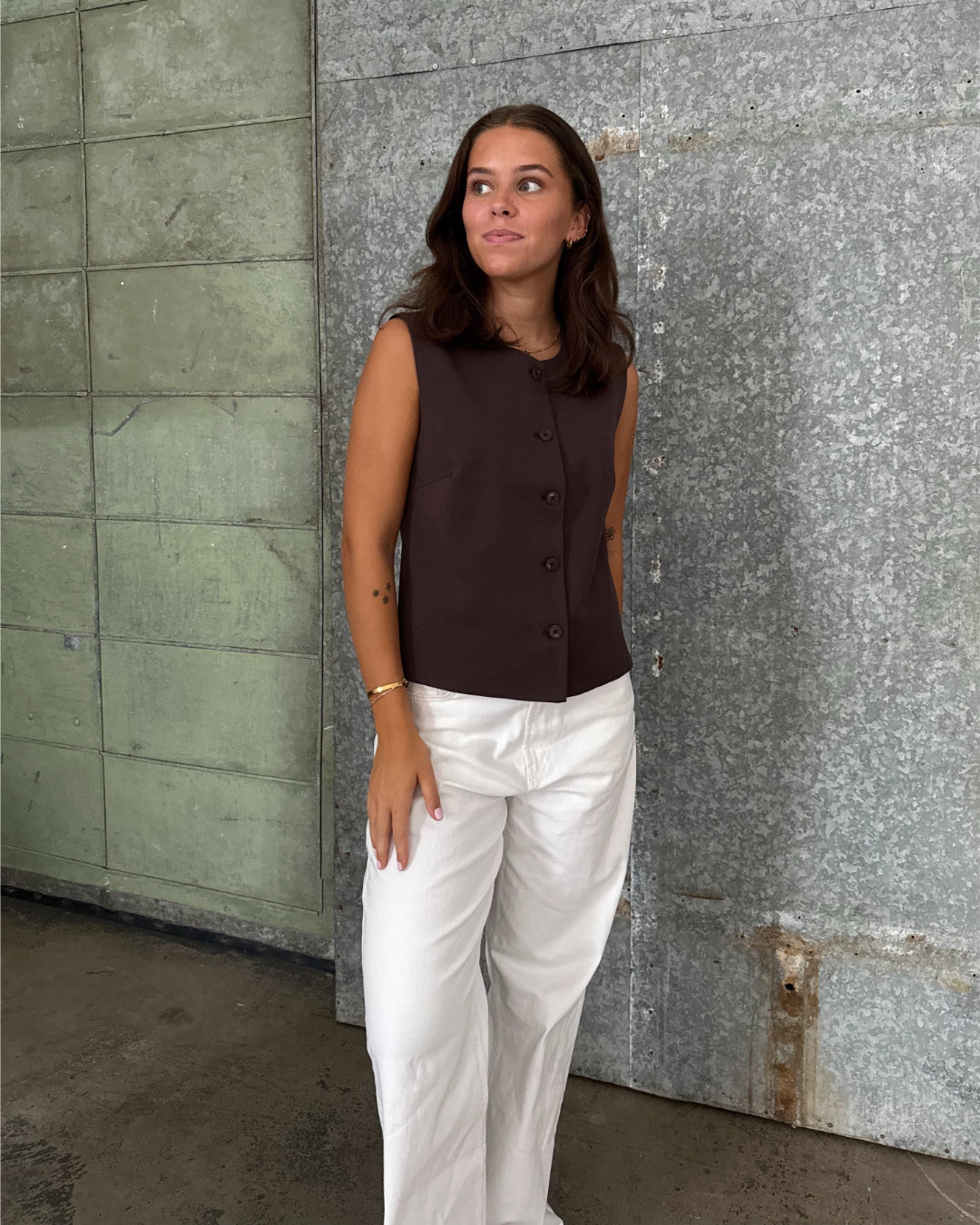 Modelfoto af pige der bærer Lisa vest i brun, samt hvide nanna jeans. Alt fra BySofieSønderby