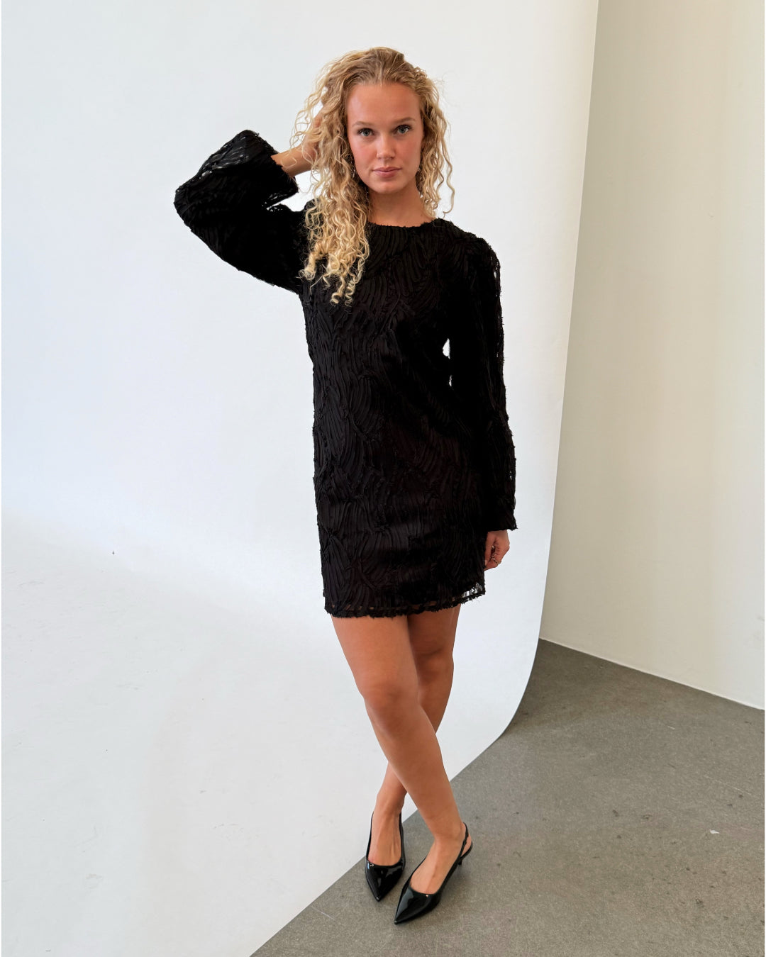 Modelfoto af pige i sort LUCIE kjole, samt sorte sko med hæl. Alt er fra BySofieSønderby.