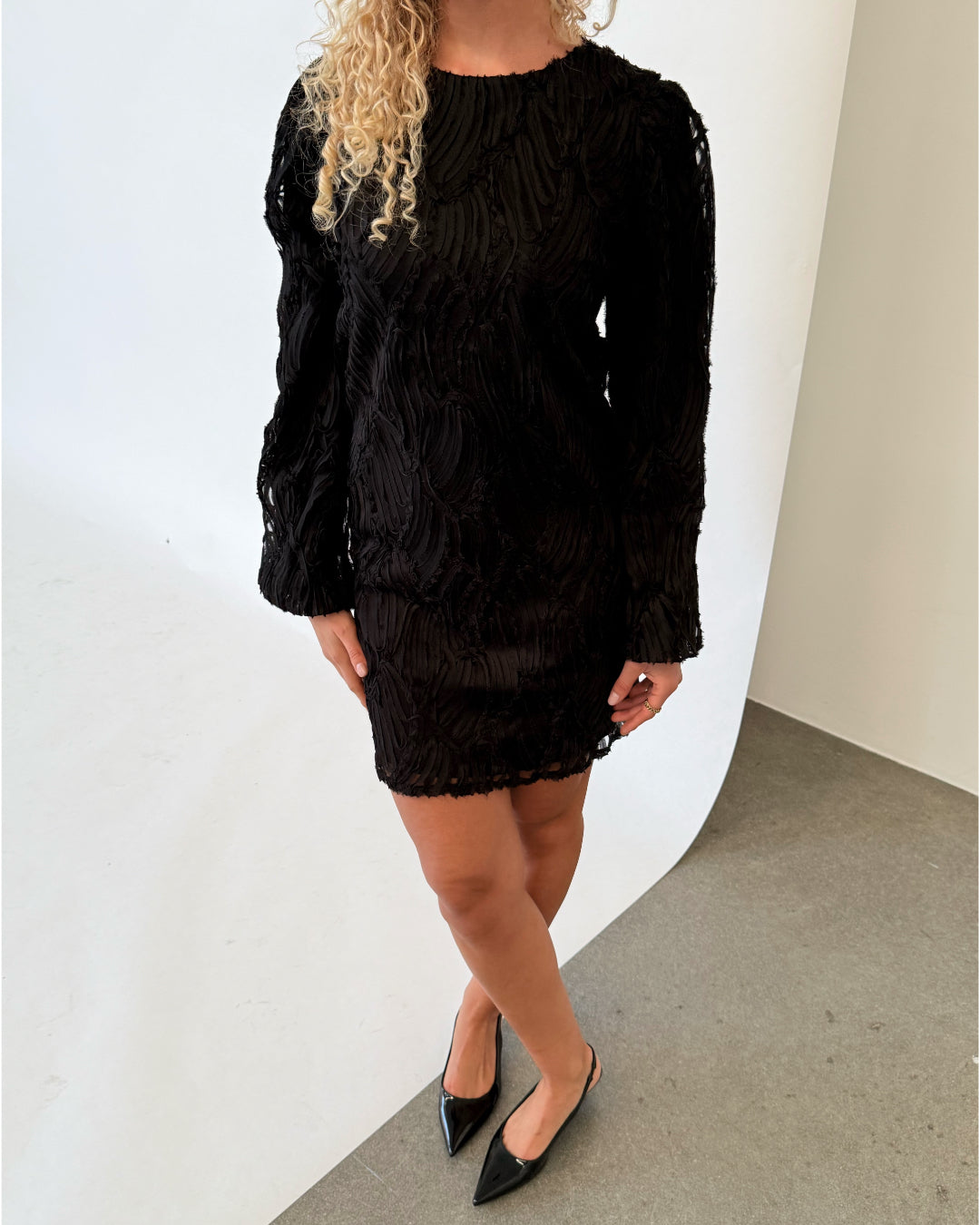 Modelfoto af pige i sort LUCIE kjole, samt sorte sko med hæl. Alt er fra BySofieSønderby.