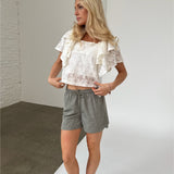 Modelfoto af pige iklædt LUCILLE blonde bluse, hvid og LANA shorts, grøn - begge fra BySofieSønderby