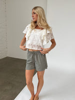 Modelfoto af pige iklædt LUCILLE blonde bluse, hvid og LANA shorts, grøn - begge fra BySofieSønderby