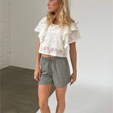 Modelfoto af pige iklædt LUCILLE blonde bluse, hvid og LANA shorts, grøn - begge fra BySofieSønderby