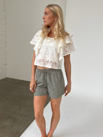 Modelfoto af pige iklædt LUCILLE blonde bluse, hvid og LANA shorts, grøn - begge fra BySofieSønderby