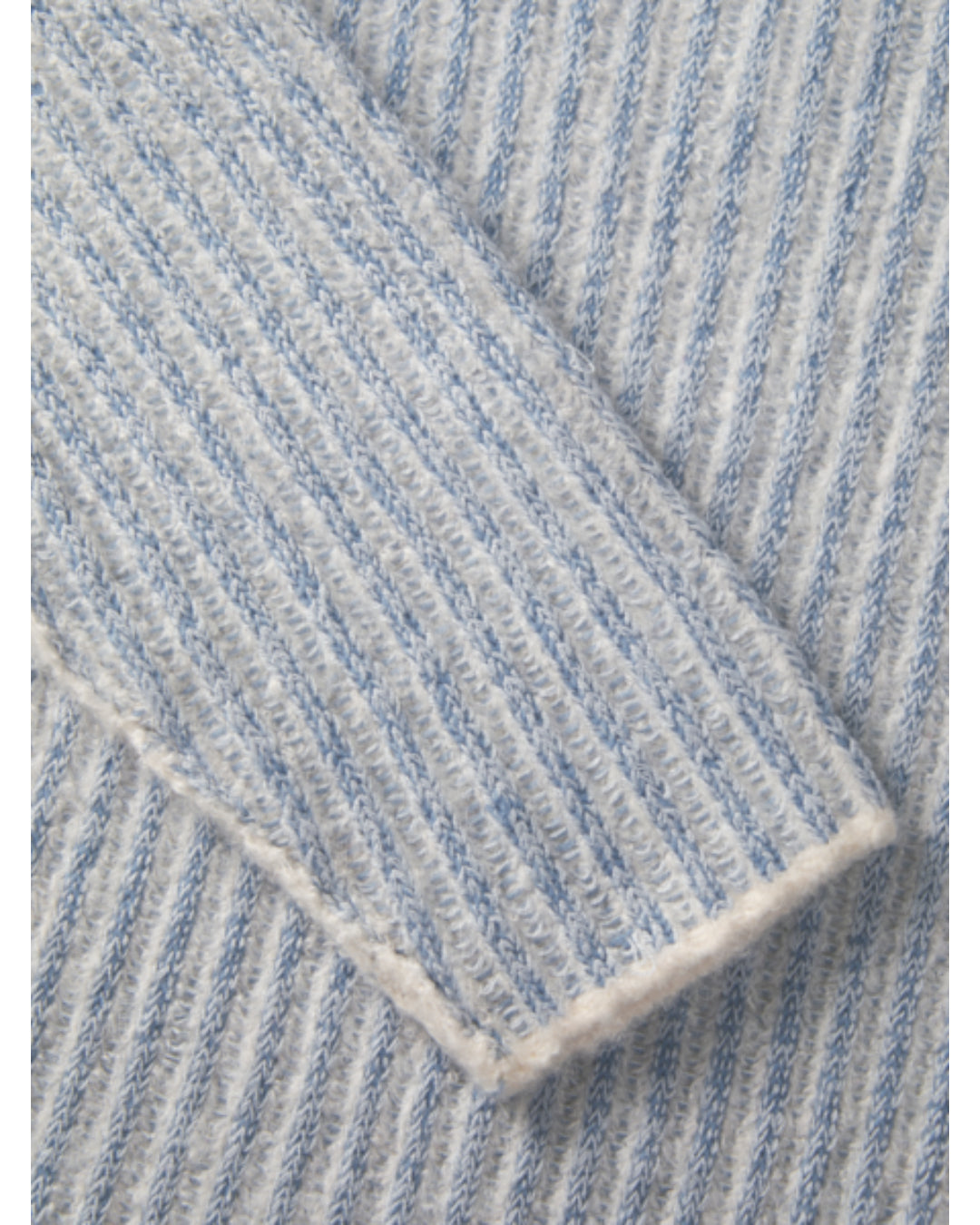 En sweater med lys blå og hvid striber ligger foldet. Teksturen er ribstrikket, hvilket giver en blød, varm fornemmelse. Den ligger fladt uden synlige baggrundselementer.