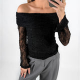 Modelfoto af pige i sort MAISY off-shoulder blondebluse og grå LISA bukser. Alt er fra BySofieSønderby.