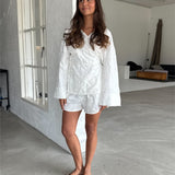 Modelfoto af pige som bærer hvid MIRANDA sæt bestående af slå-om skjorte og shorts med mønster. Alt er fra BySofieSønderby