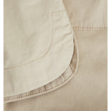 En beige lomme syet på et stykke stof med synlige stikninger. Stoffet har et glat tekstur, og syningerne er jævne. Context er en nærbillede af tekstildetaljer.