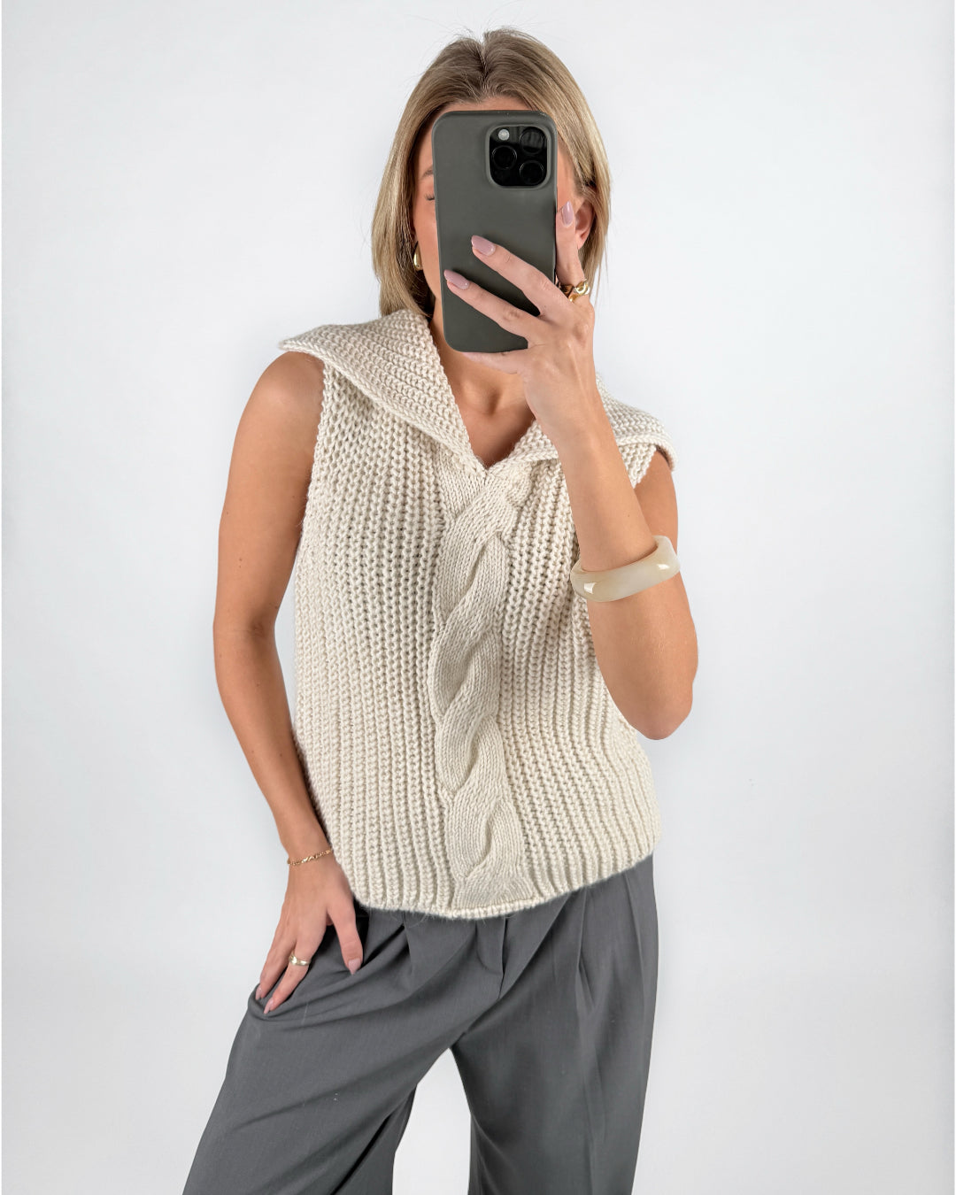 Modelfoto af pige i beige OCEAN strikvest med kabelstrik-detalje  og grå LISA bukser. Alt er fra BySofieSønderby.