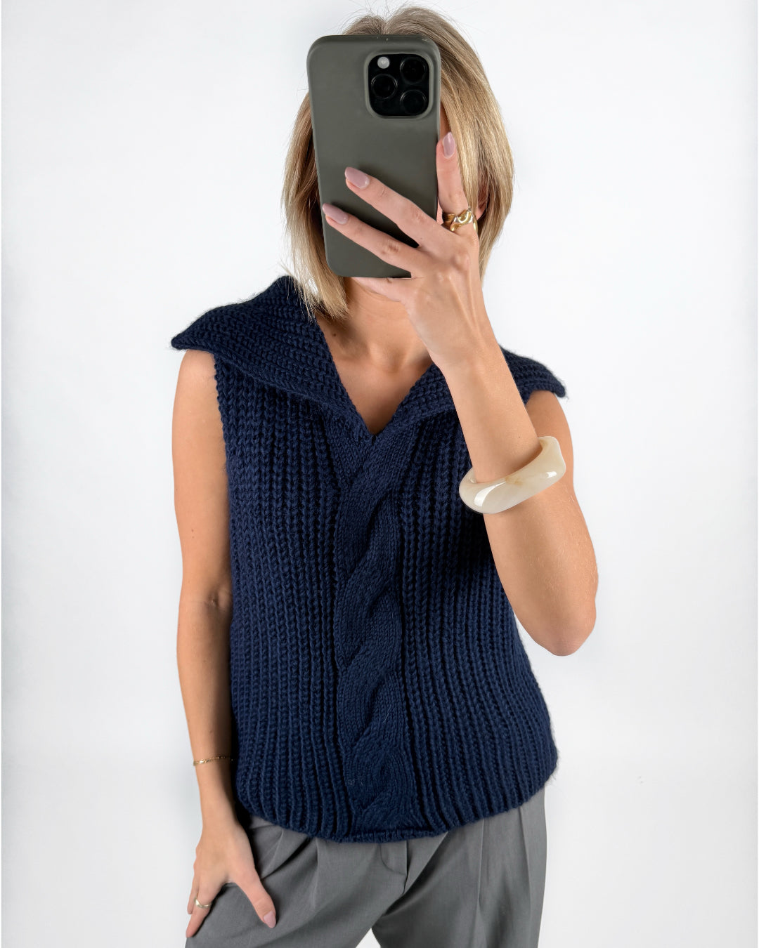 Modelfoto af pige i navy OCEAN strikvest med kabelstrik-detalje  og grå LISA bukser. Alt er fra BySofieSønderby.