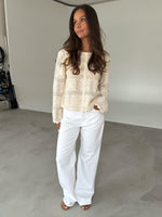 Modelfoto af pige som bærer en cremefarvet ORELLA cardigan med knapper, samt hvide jeans. Alt er fra BySofieSønderby