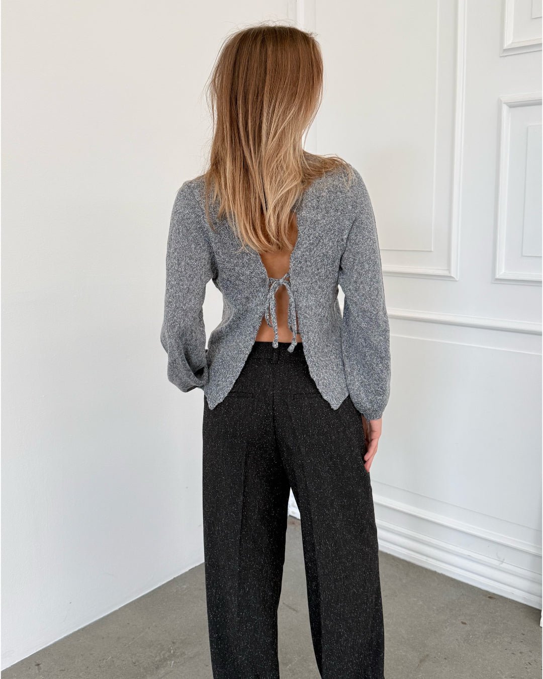 Modelfoto af pige i grå PATRICE strik, samt sortmelerede ELLIS bukser. Alt er fra BySofieSønderby.