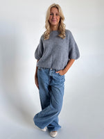 Modelfoto af pige i mørkegrå Poppy strik t-shirt og hvide Nanna jeans. Alt er fra BySofieSønderby