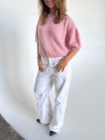 Modelfoto af pige i lyserød Poppy strik t-shirt og hvide Nanna jeans. Alt er fra BySofieSønderby
