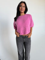 Modelfoto af pige i pink Poppy strik t-shirt og hvide Nanna jeans. Alt er fra BySofieSønderby
