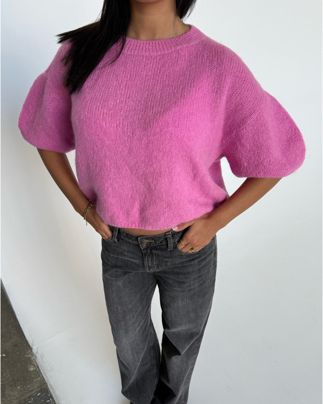 Modelfoto af pige i pink Poppy strik t-shirt og hvide Nanna jeans. Alt er fra BySofieSønderby