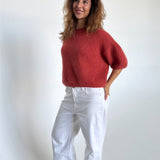 Modelfoto af pige i terracottafarvet Poppy strik t-shirt og hvide Nanna jeans. Alt er fra BySofieSønderby